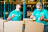 Two Lineage employees volunteer time to pack food into community food relief donation boxes for the Lineage Foundation for Good.